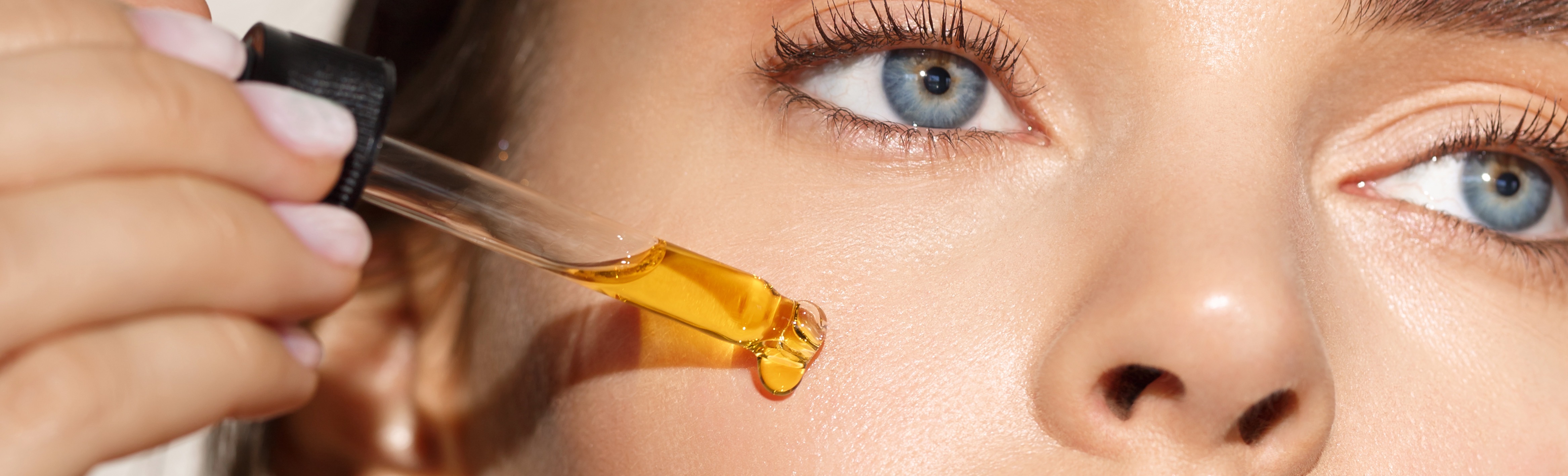 Frau mit Pipette und Arganöl im Gesicht